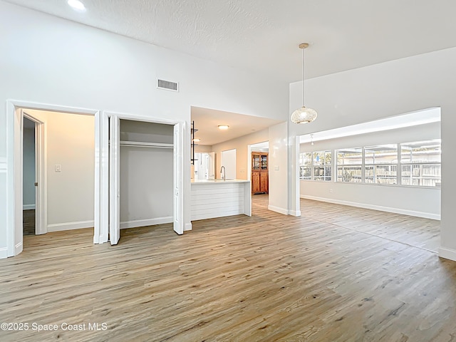 unfurnished living room with light wood-type flooring, a sink, and baseboards