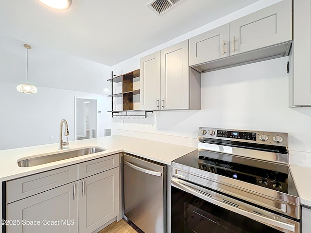 kitchen with stainless steel appliances, a sink, open shelves, light countertops, and gray cabinetry