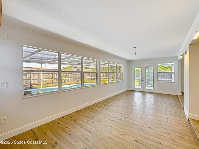 spare room featuring baseboards, light wood-style floors, and french doors