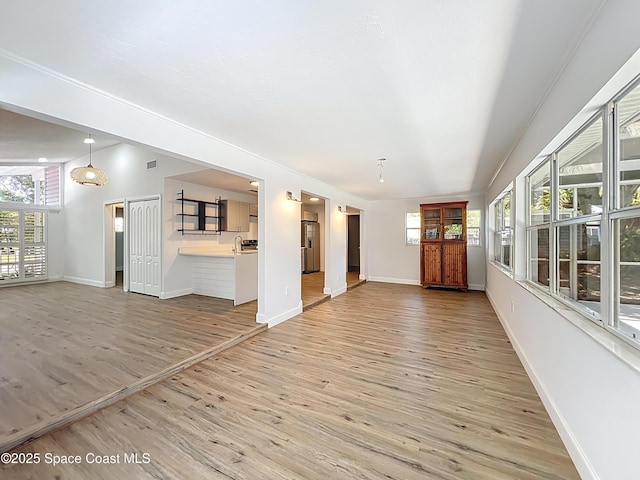 unfurnished living room with light wood-type flooring and baseboards