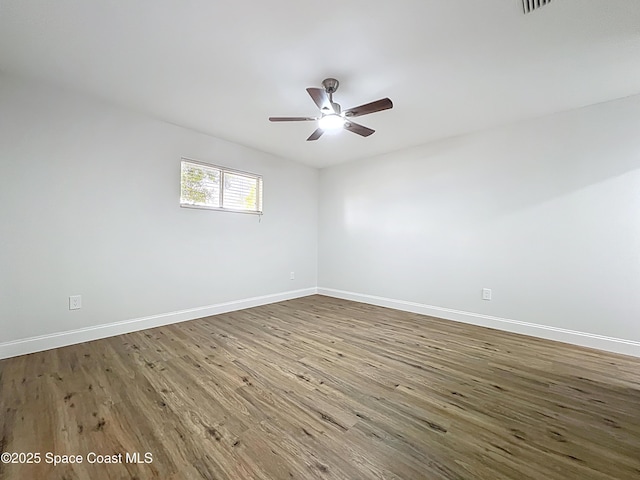 empty room with wood finished floors, baseboards, and a ceiling fan