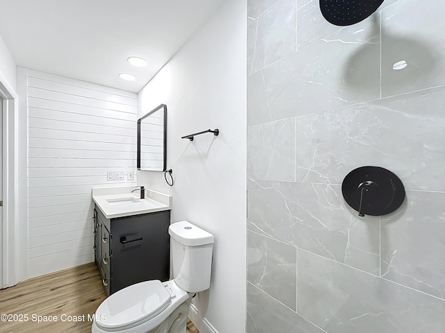 full bathroom with wood finished floors, vanity, toilet, and tiled shower