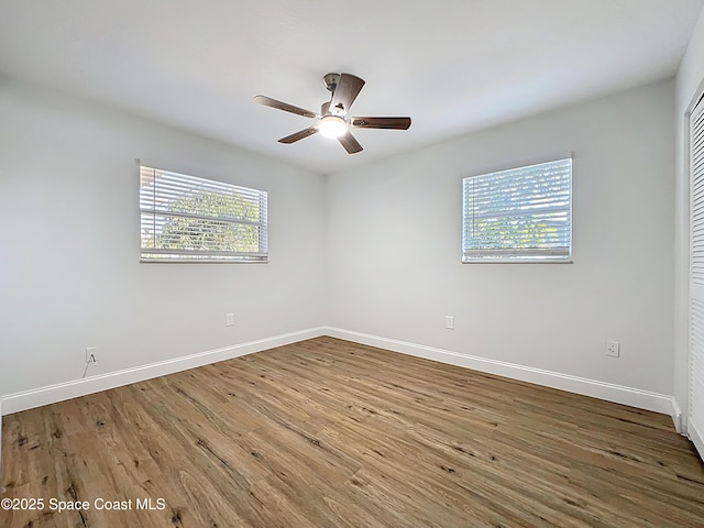 empty room with baseboards, wood finished floors, and ceiling fan