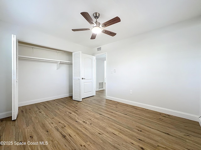 unfurnished bedroom with wood finished floors, a closet, baseboards, and a ceiling fan