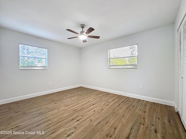unfurnished bedroom featuring a closet, multiple windows, wood finished floors, and baseboards