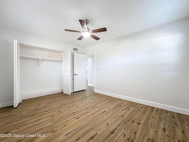 unfurnished bedroom with wood finished floors, baseboards, a closet, and ceiling fan