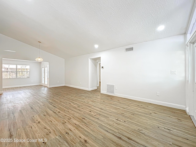 empty room featuring light wood-type flooring, baseboards, lofted ceiling, a textured ceiling, and recessed lighting