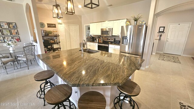 5290 Cinnamon Fern Blvd, Cocoa, FL 32927 - kitchen featuring stainless steel appliances, a sink, arched walkways, light tile patterned floors, and a kitchen bar