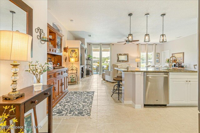 5290 Cinnamon Fern Blvd, Cocoa, FL 32927 - kitchen featuring stainless steel dishwasher, open floor plan, white cabinetry, stone counters, and decorative light fixtures