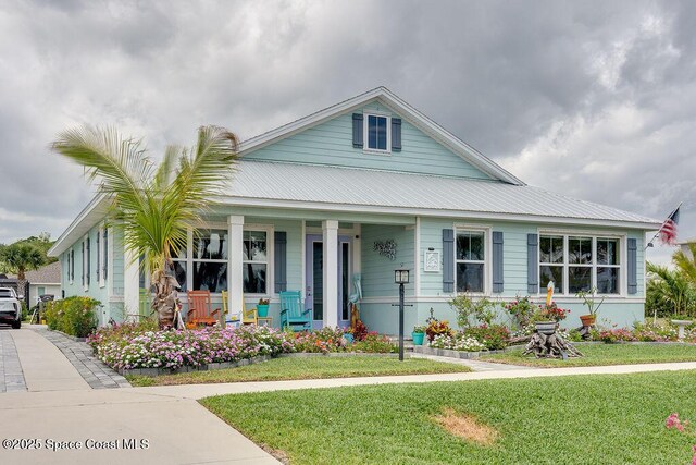 5250 Riveredge Dr, Titusville, FL 32780 - view of front facade with a porch, a front lawn, and metal roof