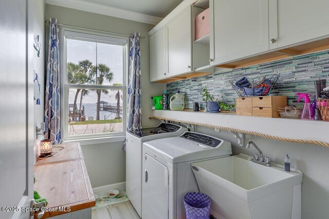 5250 Riveredge Dr, Titusville, FL 32780 - clothes washing area with independent washer and dryer, ornamental molding, baseboards, cabinet space, and light wood-style flooring