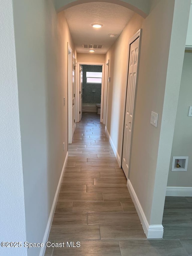 1042 Hickory Ln, Cocoa, FL 32922 - hallway with arched walkways, wood finished floors, and baseboards