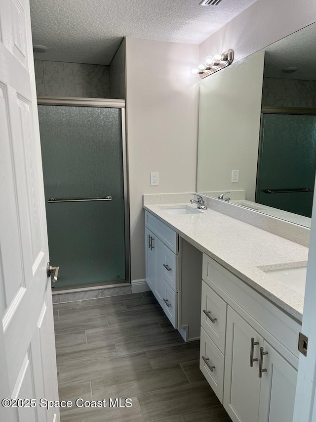 1042 Hickory Ln, Cocoa, FL 32922 - full bath featuring a shower stall, double vanity, a textured ceiling, and wood finish floors