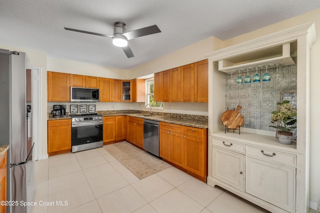 2007 Oak St, Melbourne Beach, FL 32951 - kitchen with stainless steel appliances, a sink, ceiling fan, brown cabinetry, and glass insert cabinets
