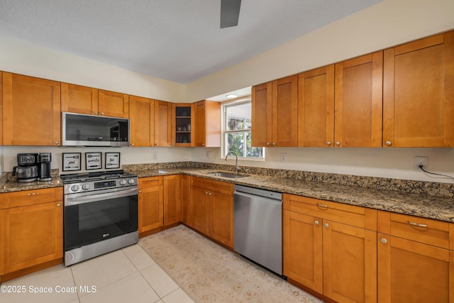 2007 Oak St, Melbourne Beach, FL 32951 - kitchen with appliances with stainless steel finishes, a sink, dark stone countertops, and brown cabinets