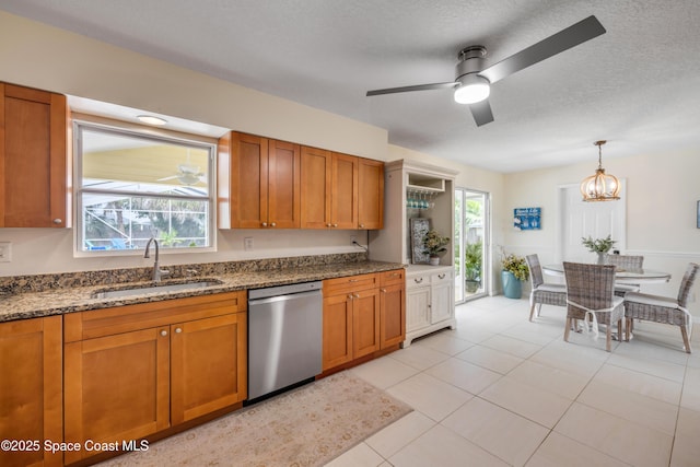 2007 Oak St, Melbourne Beach, FL 32951 - kitchen with stainless steel dishwasher, a sink, brown cabinetry, dark stone counters, and a textured ceiling