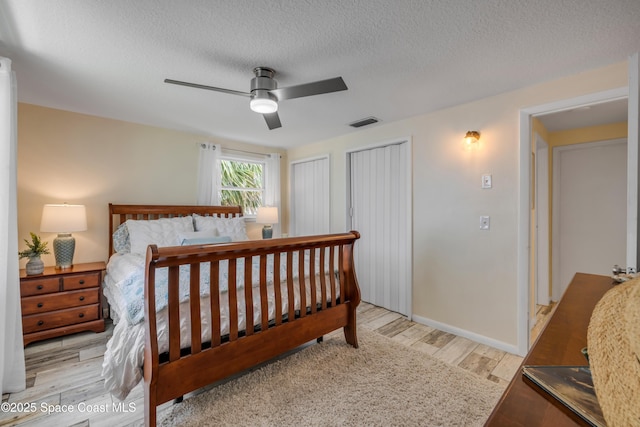 2007 Oak St, Melbourne Beach, FL 32951 - bedroom featuring two closets, light wood-style flooring, a ceiling fan, a textured ceiling, and baseboards