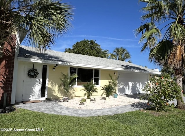 2007 Oak St, Melbourne Beach, FL 32951 - back of house with an attached garage, roof with shingles, and a lawn