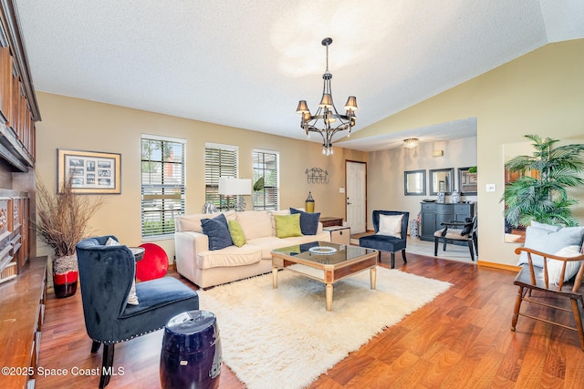 6855 Bryant Rd, Cocoa, FL 32927 - living room featuring wood finished floors, a chandelier, vaulted ceiling, a textured ceiling, and baseboards