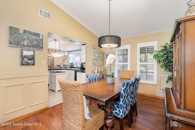 6855 Bryant Rd, Cocoa, FL 32927 - dining room with a chandelier, dark wood finished floors, healthy amount of natural light, lofted ceiling, and a textured ceiling
