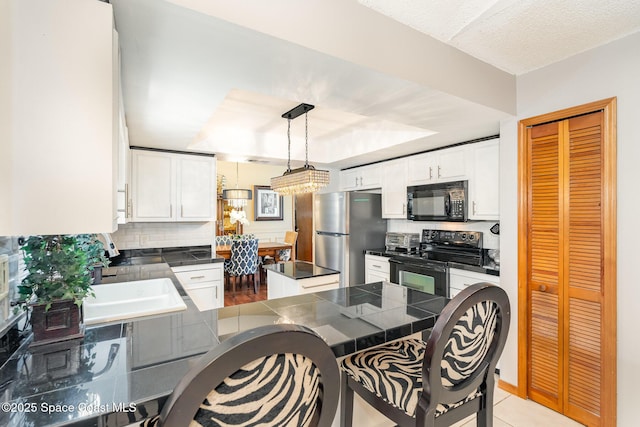 6855 Bryant Rd, Cocoa, FL 32927 - kitchen featuring black appliances, dark countertops, a peninsula, white cabinetry, and a tray ceiling
