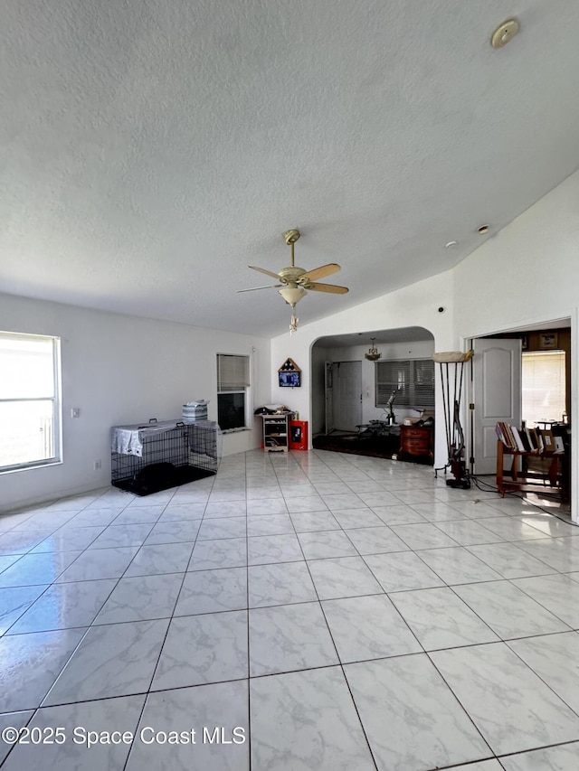 1112 Pine Creek Cir NE, Palm Bay, FL 32905 - living area featuring a textured ceiling, lofted ceiling, a ceiling fan, and arched walkways