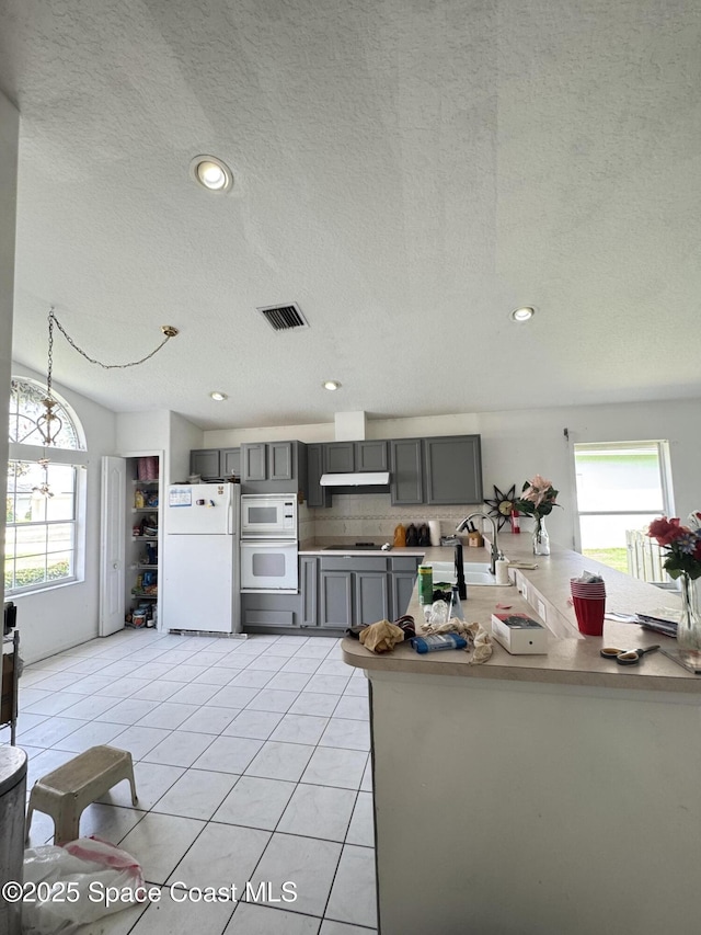 1112 Pine Creek Cir NE, Palm Bay, FL 32905 - kitchen featuring white appliances, gray cabinets, a textured ceiling, light tile patterned floors, and tasteful backsplash