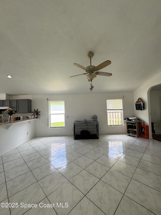 1112 Pine Creek Cir NE, Palm Bay, FL 32905 - living room featuring healthy amount of natural light, light marble finish floors, ceiling fan, and a textured ceiling
