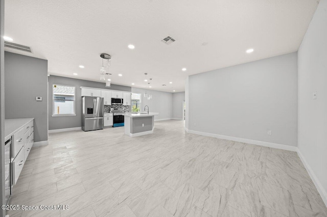 3350 Nancy St, West Melbourne, FL 32904 - kitchen featuring appliances with stainless steel finishes, open floor plan, white cabinetry, light countertops, and a center island with sink