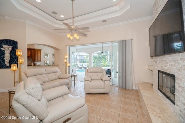 4178 Ventana Blvd, Rockledge, FL 32955 - living area featuring a ceiling fan, light tile patterned floors, crown molding, a raised ceiling, and a fireplace