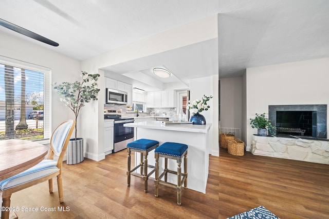 kitchen with stainless steel appliances, light wood-type flooring, white cabinets, and a sink