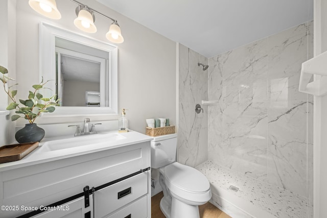 bathroom featuring a marble finish shower, vanity, and toilet