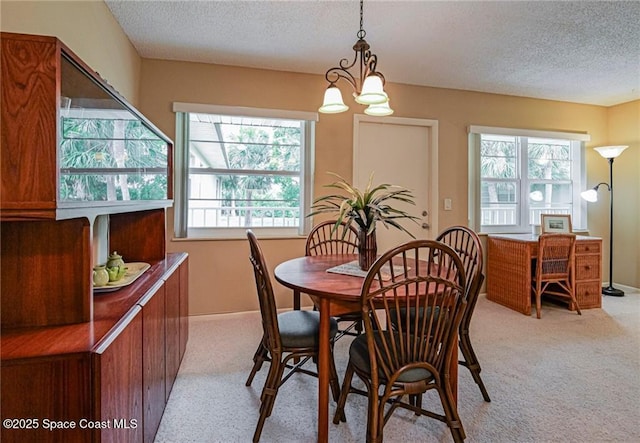 dining space featuring a textured ceiling, light carpet, healthy amount of natural light, and a chandelier