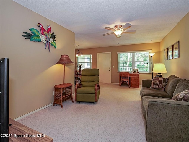 living area with carpet, a ceiling fan, a textured ceiling, a chandelier, and baseboards