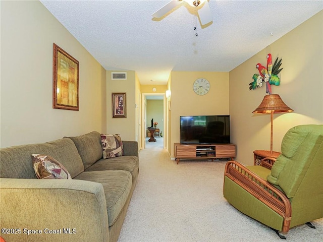 living room with carpet flooring, ceiling fan, and a textured ceiling