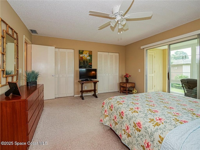 bedroom with multiple closets, access to exterior, light colored carpet, a textured ceiling, and a ceiling fan