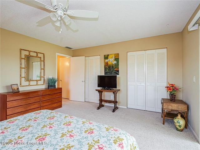 bedroom featuring two closets, light carpet, a ceiling fan, and baseboards