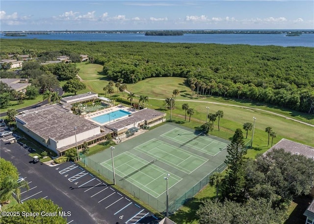 aerial view of a nearby body of water, a pool area, and a heavily wooded area