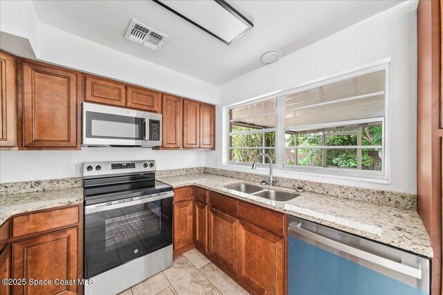 133 Lee Rd, Melbourne, FL 32904 - kitchen with stainless steel appliances, a sink, light stone counters, and brown cabinetry