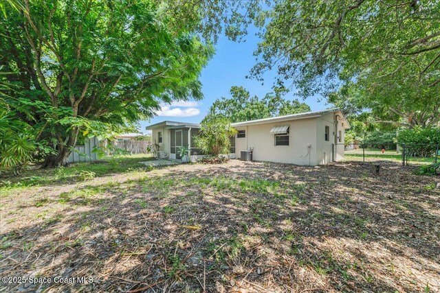 133 Lee Rd, Melbourne, FL 32904 - rear view of house featuring a sunroom, a fenced backyard, stucco siding, and central AC unit