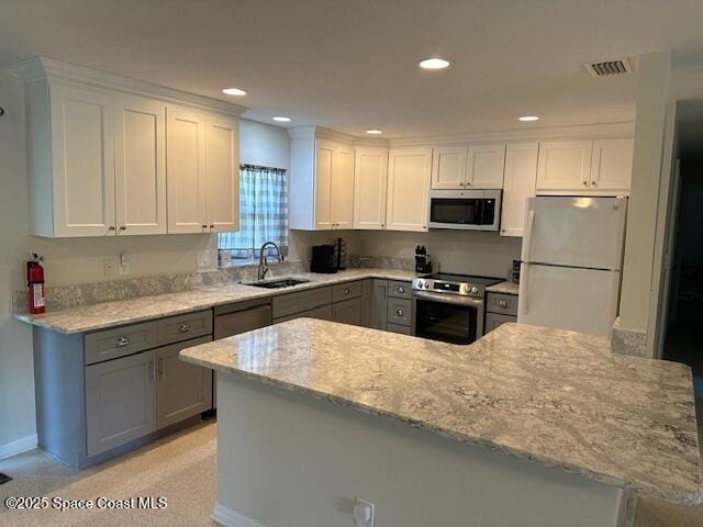 kitchen with appliances with stainless steel finishes, a sink, gray cabinetry, white cabinets, and recessed lighting