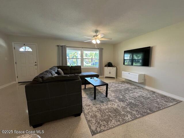 living room featuring a ceiling fan, baseboards, carpet floors, and a textured ceiling