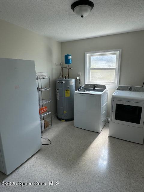 laundry room featuring water heater, washer and dryer, and a textured ceiling