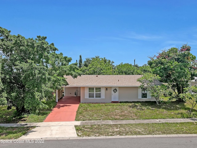 view of front of house with a carport, driveway, stucco siding, a shingled roof, and a front lawn