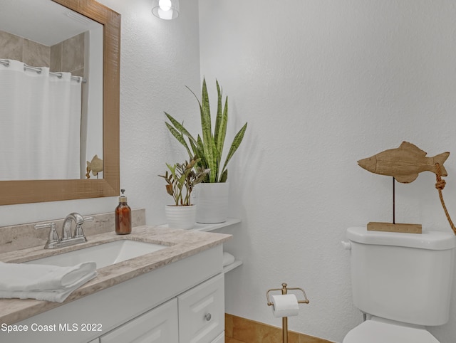 bathroom featuring toilet, vanity, a shower with shower curtain, and a textured wall