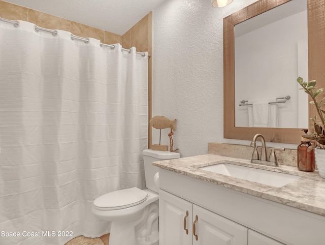 bathroom with a textured wall, toilet, and vanity