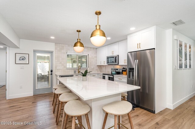 8103 Magnolia Ave, Cape Canaveral, FL 32920 - kitchen with stainless steel appliances, baseboards, light wood finished floors, a kitchen bar, and recessed lighting