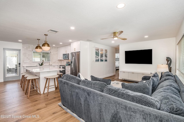 8103 Magnolia Ave, Cape Canaveral, FL 32920 - living room featuring light wood-type flooring, a ceiling fan, recessed lighting, baseboards, and a textured ceiling
