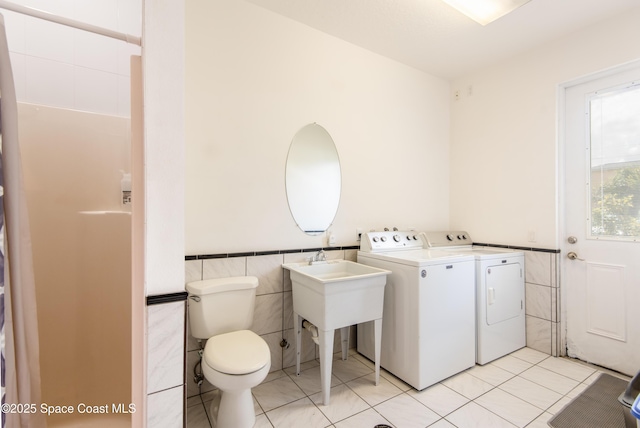 7030 Livingstone Ln, Melbourne, FL 32904 - laundry room with tile walls, independent washer and dryer, wainscoting, and light tile patterned floors