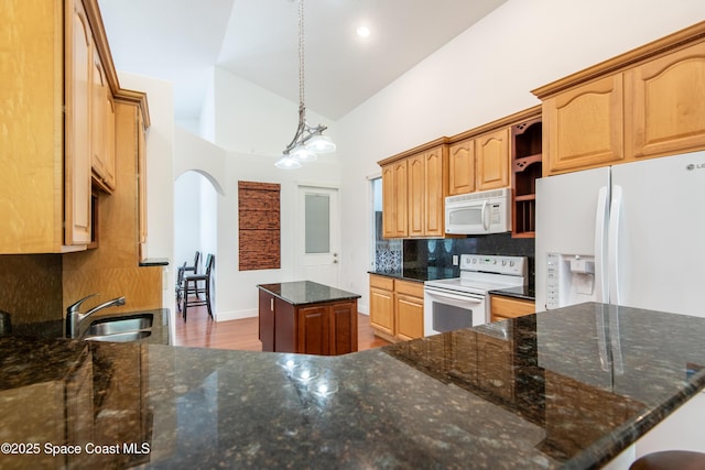 7030 Livingstone Ln, Melbourne, FL 32904 - kitchen with white appliances, a kitchen island, tasteful backsplash, a sink, and arched walkways